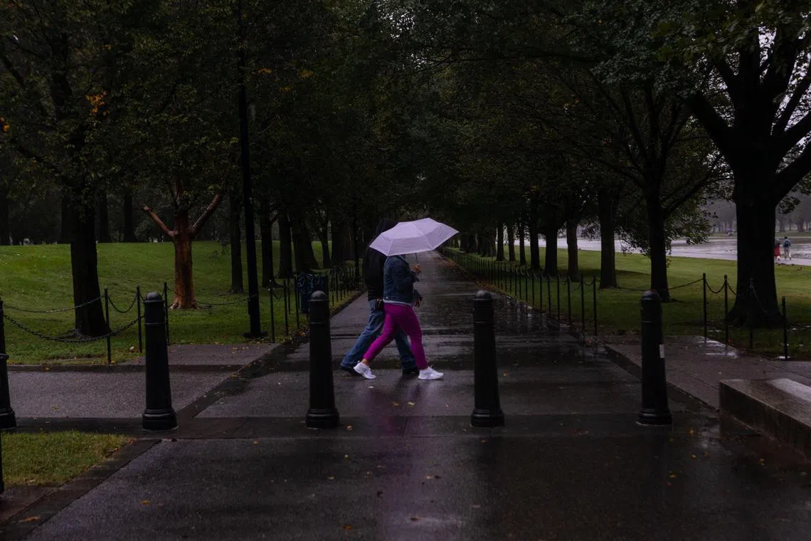 WASHINGTON, DC - SEPTEMBER 23: People walk through the rain toward the Lincoln Memorial reflecting pool on September 23, 2023 in Washington, DC. Tropical Storm Ophelia brought waves of heavy wind and rain to the district, with residents bracing for potential flooding and power outages.   Anna Rose Layden/Getty Images/AFP (Photo by Anna Rose Layden / GETTY IMAGES NORTH AMERICA / Getty Images via AFP)