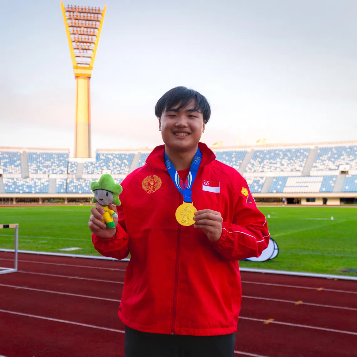 Singaporean thrower Anson Loh posing with the boys' shot put gold medal he won at the Asean School Games.