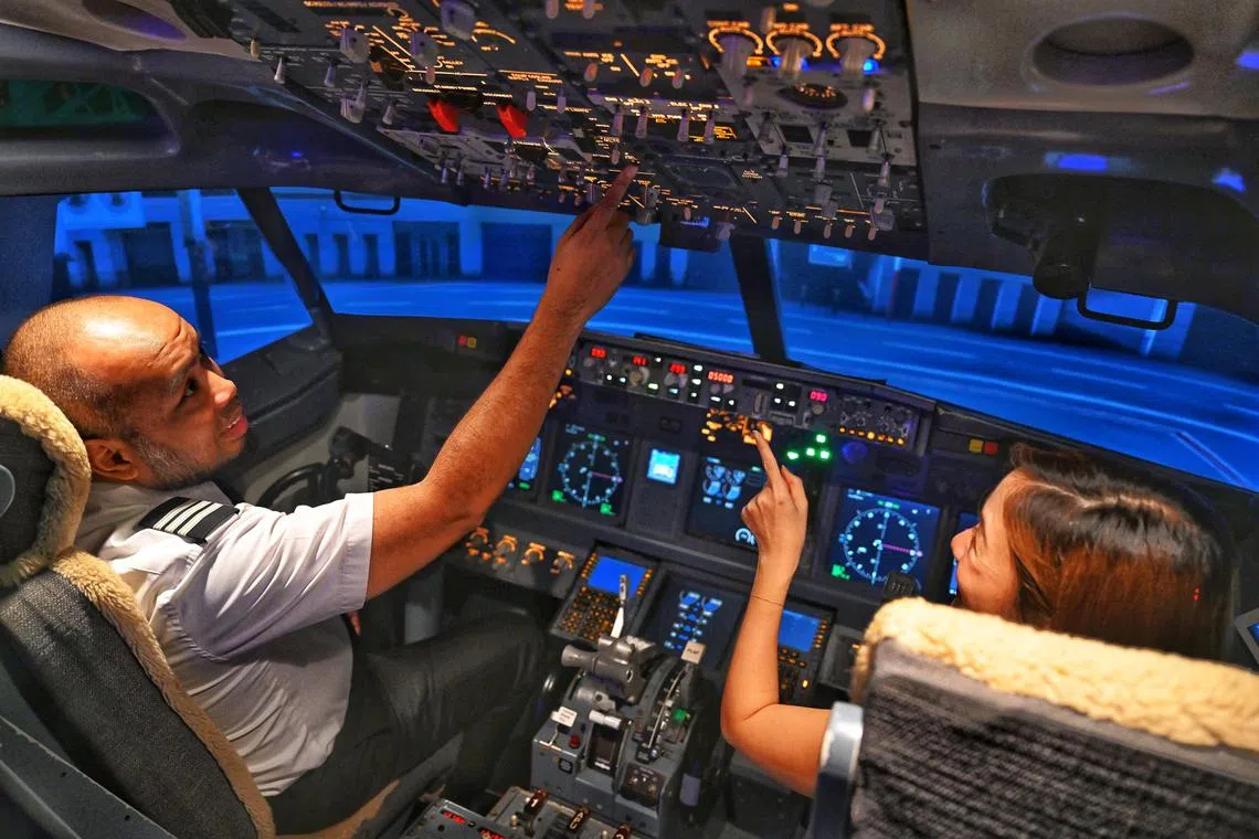 From left: Senior first officer Hamdan Bin Mohamed Khamis coaching ST journalist Louisa Lim at the flight simulator on August 8, 2024