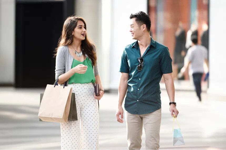 Indian woman and Chinese man holding shopping bags and shopping along Orchard Road