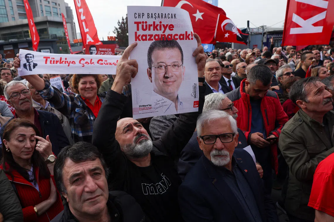 A supporter of the main opposition Republican People's Party (CHP) holds a poster featuring a picture of jailed Istanbul Mayor Ekrem Imamoglu and a slogan \"CHP will succeed, Turkey will win\" reads on it, during a protest near the Justice Palace, known as Caglayan Courthouse, as Imamoglu testifies in a new investigation over alleged espionage, in Istanbul, Turkey, October 26, 2025. REUTERS/Dilara Senkaya