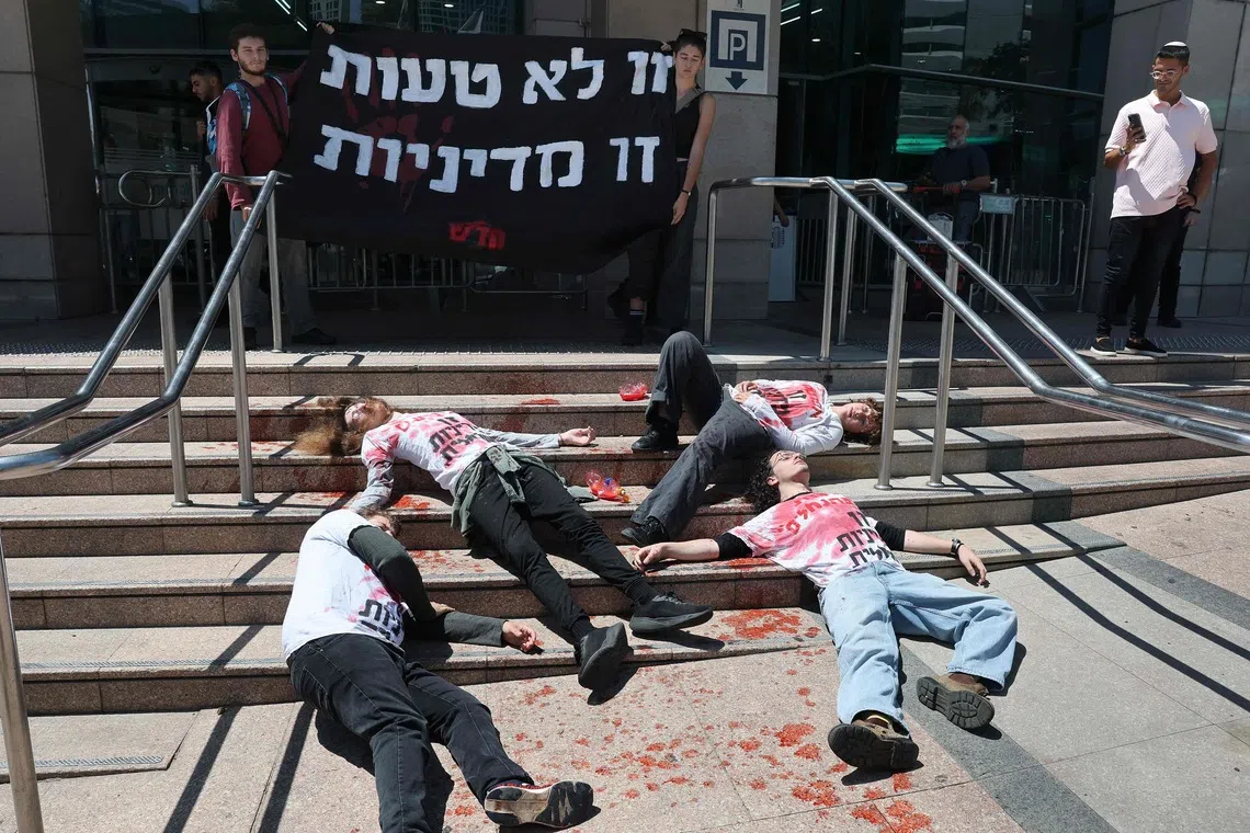 TOPSHOT - Activists in red-stained T-shirts take part in a die-in protest in the Israeli coastal city of Tel Aviv on August 19, 2026, against recent violent attacks by Israeli settlers in the Israeli-occupied West Bank. Violence against Palestinians by Israeli settlers in the West Bank has increased dramatically since the October 7, 2023 attack on Israel by Hamas from the Gaza Strip. More than 500,000 Israelis live in settlements in the West Bank, which are illegal under international law, among some three million Palestinians in the territory. (Photo by JACK GUEZ / AFP)