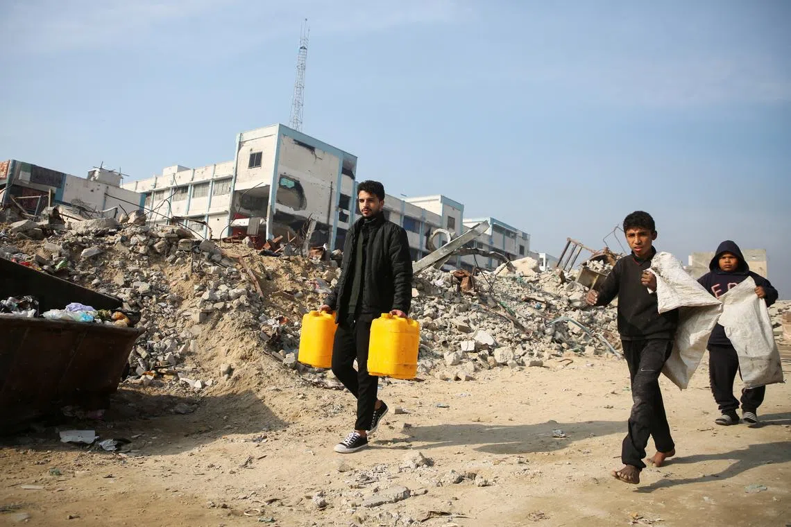 Palestinians walk past the rubble of buildings destroyed in previous Israeli strikes, ahead of a ceasefire set to take effect on Sunday, in Khan Younis in the southern Gaza Strip January 16, 2025. REUTERS/Hatem Khaled