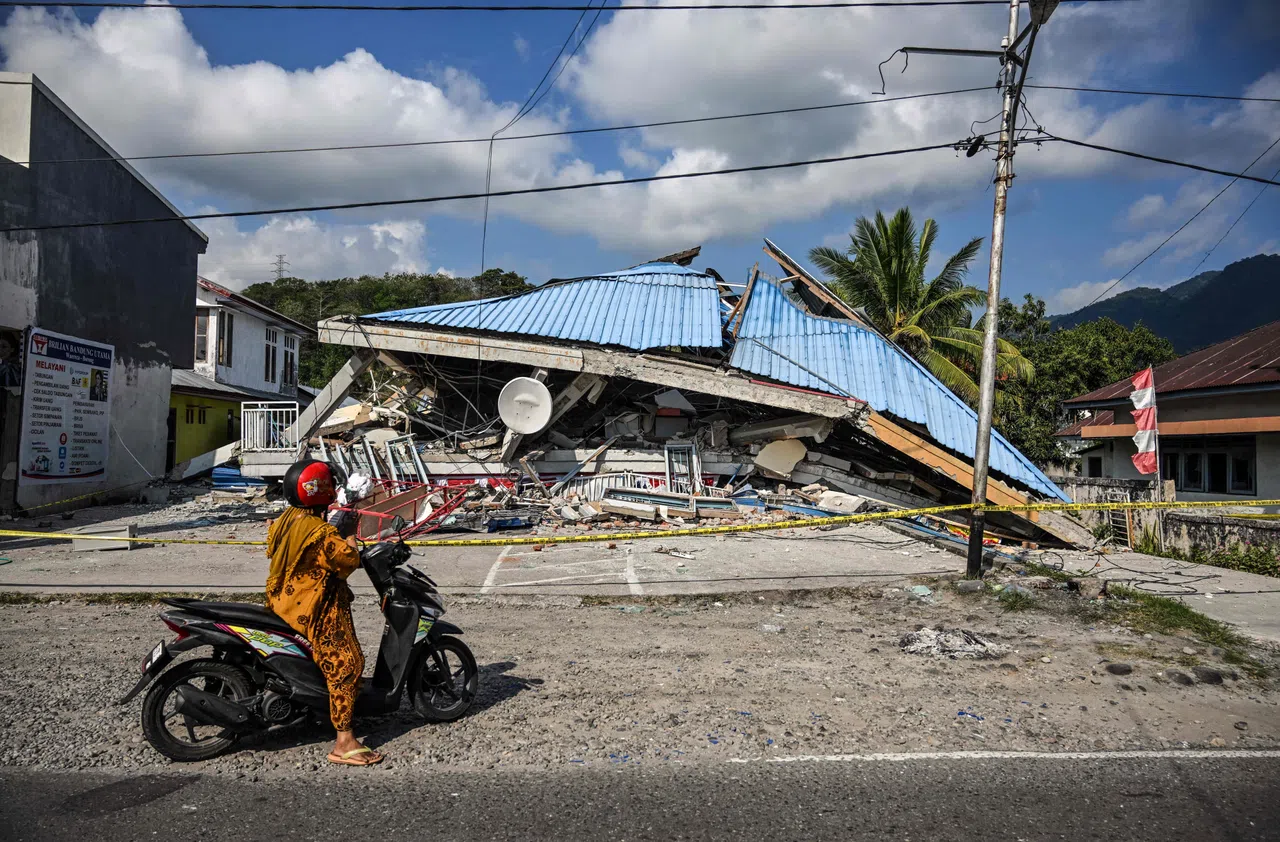 A motorbike stops next to a collapsed building following a 7.7-magnitude earthquake in Borong, East Manggarai, East Nusa Tenggara on August 16, 2026. Help started arriving on August 16 for thousands of evacuees on Indonesia's Flores island after a powerful earthquake killed 51 people, injured dozens and damaged hundreds of houses and buildings. (Photo by JUNI KRISWANTO / AFP)