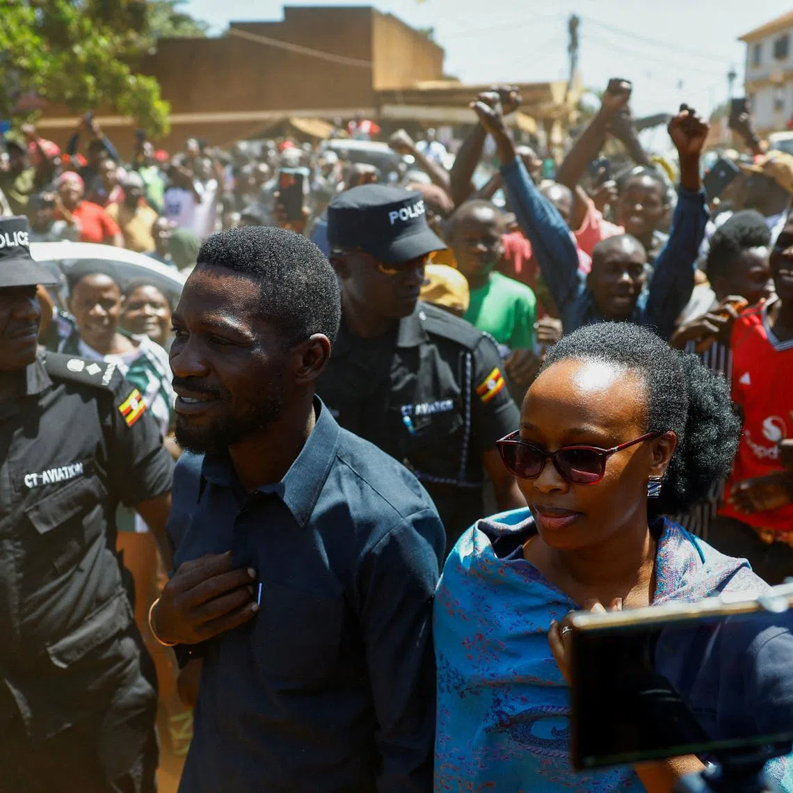 Ugandan Presidential candidate Robert Kyagulanyi, also known as Bobi Wine, of the National Unity Platform (NUP) party, flanked by his wife Barbara Kyagulanyi are escorted by police and supporters as they arrive to cast their votes in the general election, within Magere neighborhood of Kasangati district in Kampala, Uganda January 15, 2026. REUTERS/Thomas Mukoya