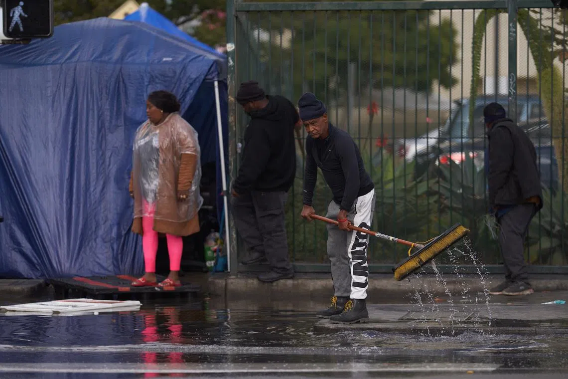 A man tries to clear a flooded sidewalk during a bomb cyclone rain storm in downtown Los Angeles, California, USA, Jan 5, 2023.