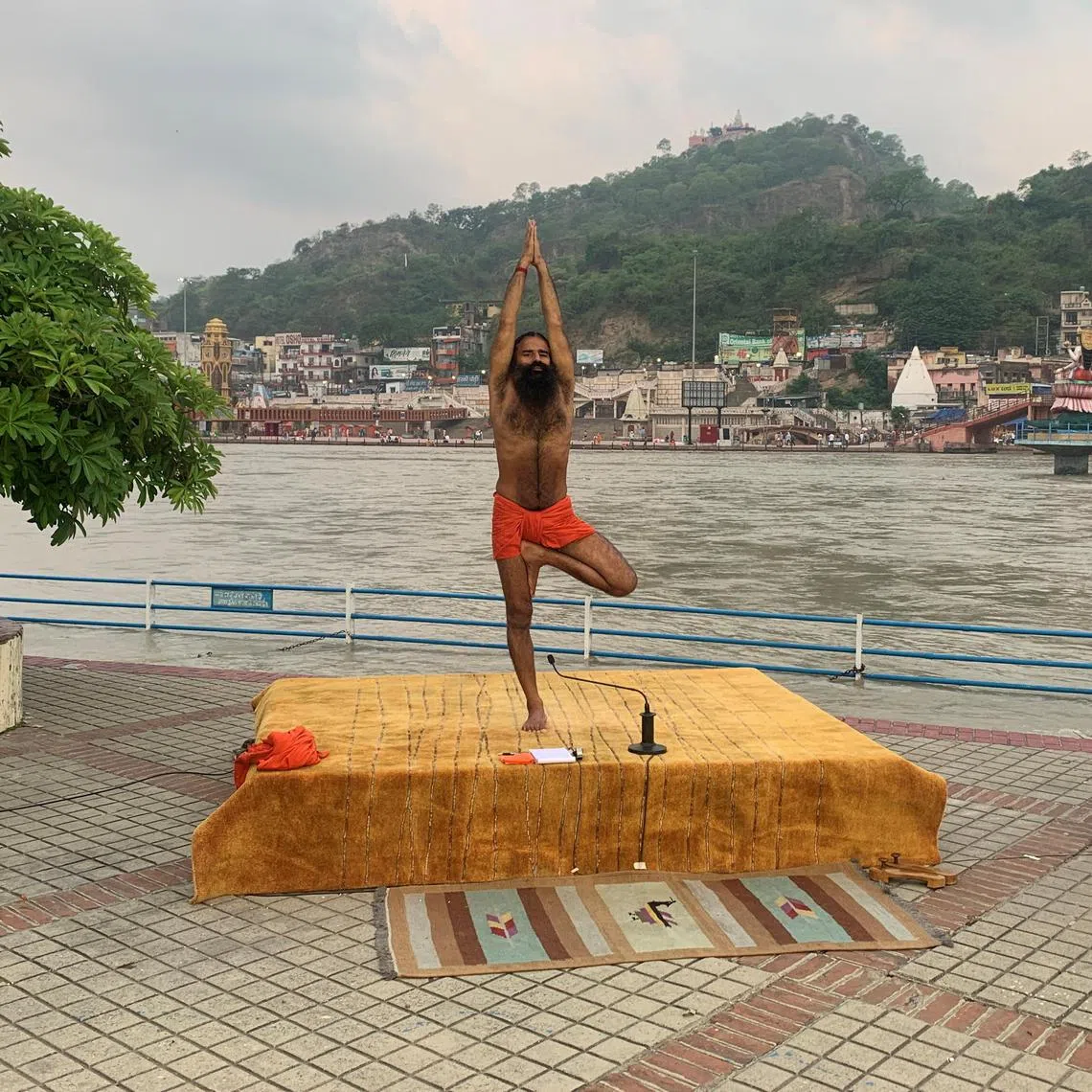 FILE PHOTO: India's yoga guru Baba Ramdev performs yoga on the banks of the river Ganges ahead of International Yoga day, in the northern town of Haridwar, India, June 19, 2020. Picture taken June 19, 2020. REUTERS/Sunil Kataria/File Photo