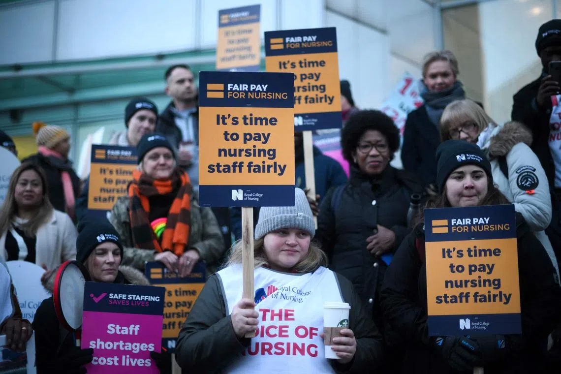 Striking nurses hold signs at a picket line outside University College Hospital in London on January 19, 2023. 