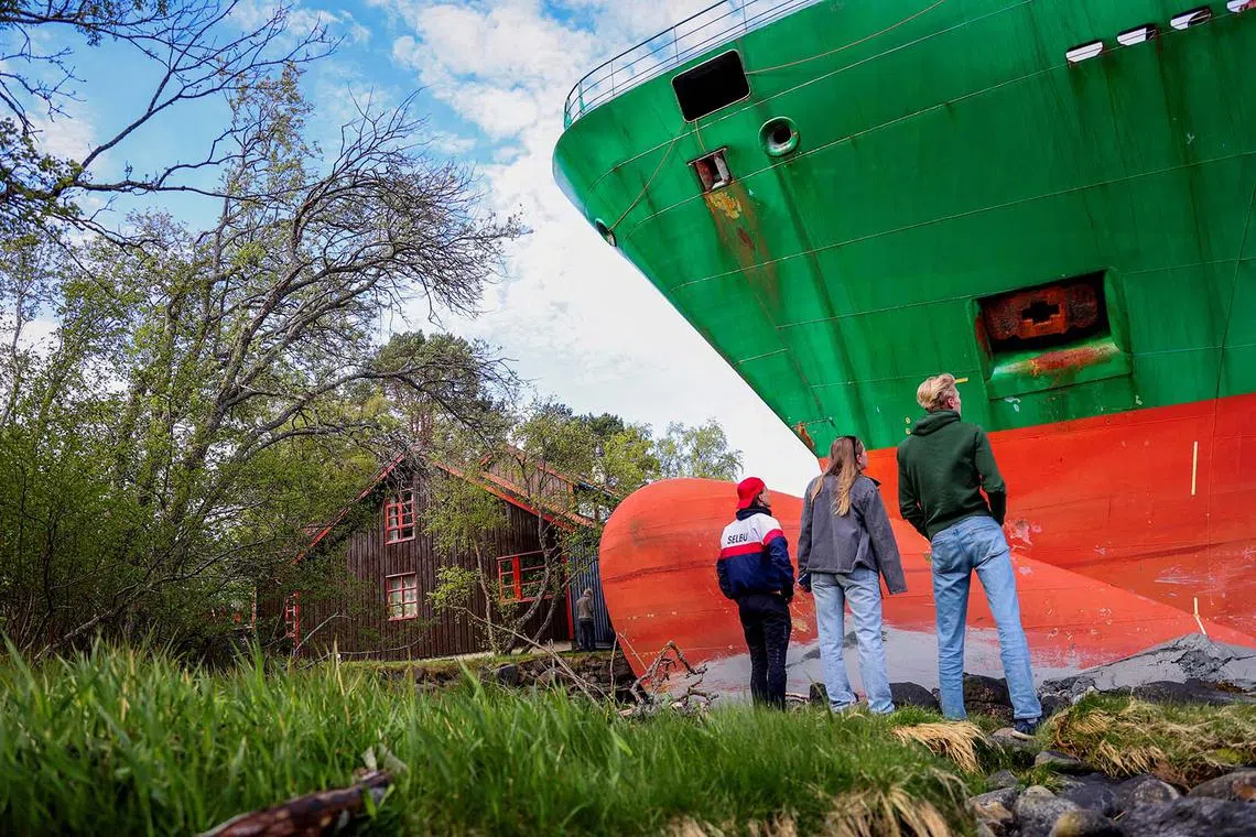 People standing near a container ship, which almost hit a house, in Trondheim, Norway, May 22, 2025. 