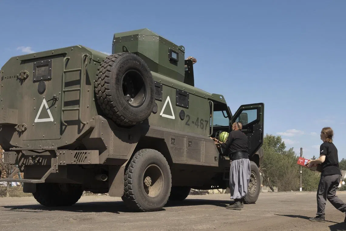 A volunteer - the father of a fallen Ukrainian soldier - and his granddaughter distribute watermelons and food to servicemen on a road in Ukraine's Sumy region, near the border with Russia.