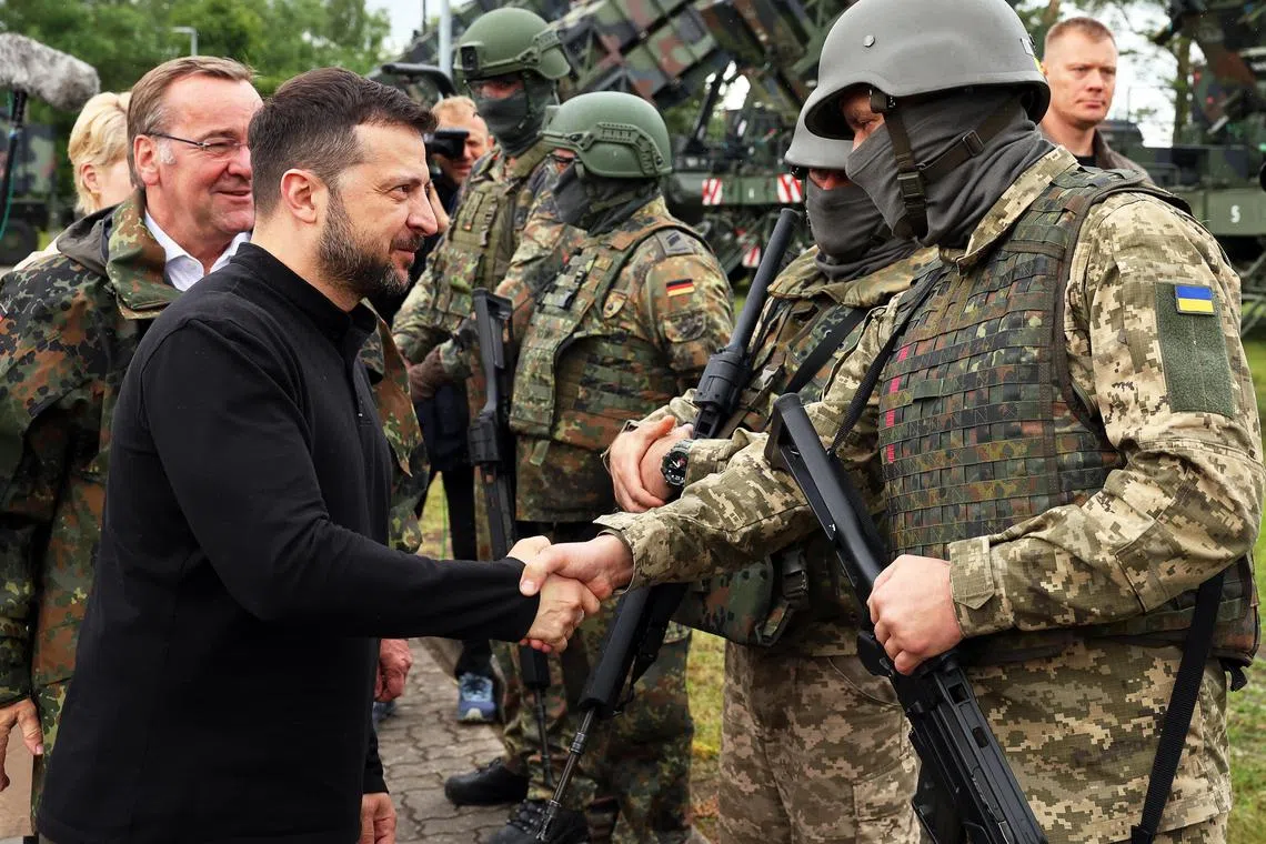 German Defence Minister Boris Pistorius (just seen) and Ukrainian President Volodymyr Zelensky meet German and Ukrainian soldiers during a visit to a German military training ground, where Ukrainian servicemen are learning how to operate the Patriot air defence missile system.