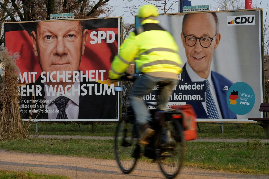 FILE PHOTO: A cyclist rides past election campaign posters for CDU party leader and top candidate for chancellor Friedrich Merz and Social Democratic Party (SPD) Chancellor Olaf Scholz, ahead of the upcoming general election in Schenefeld near Hamburg, Germany February 10, 2025. REUTERS/Fabian Bimmer/File Photo