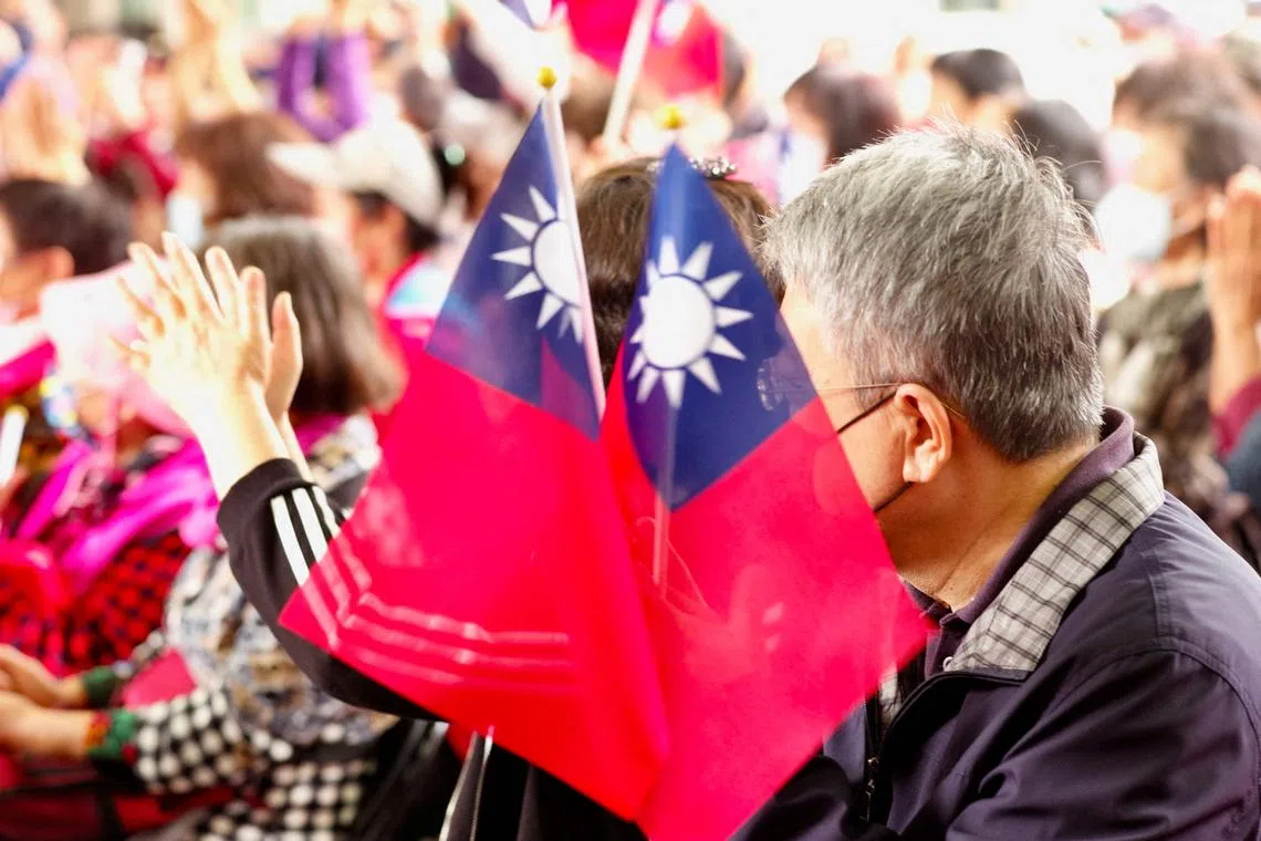 Supporters of Chiang Wan-an, grandson of the late president Chiang Kai-shek from the main opposition Kuomintang (KMT) hold flags while listening to his elections campaign in New Taipei City on November 5, 2022. (Photo by Sam Yeh / AFP)