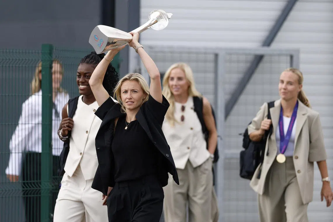 England's Leah Williamson holding the trophy aloft on July 28 next to Michelle Agyemang, as they arrive at London's Southend Airport after winning the Uefa Women's Euro 2025 competition.