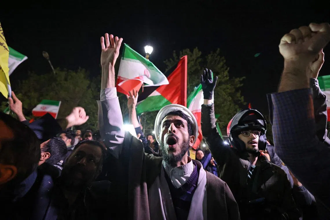 Demonstrators wave Iran's flag and Palestinian flags as they gather in front of the British Embassy in Tehran on April 14, 2024.