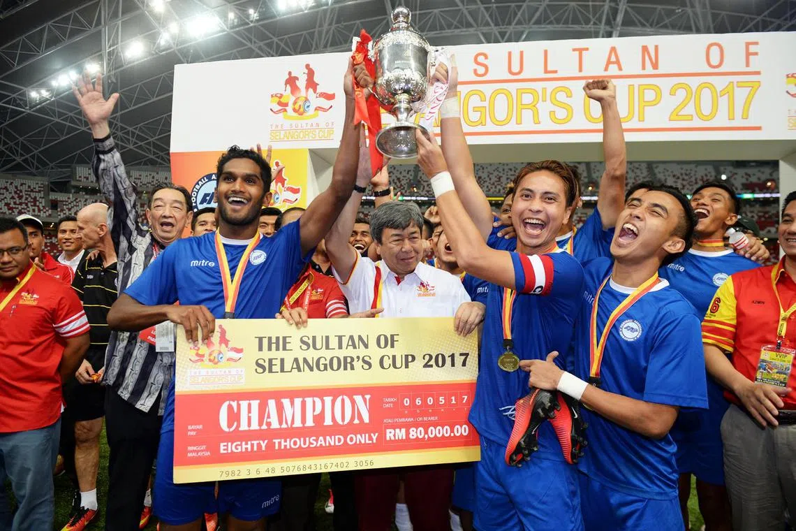 Singapore Selection team mates, Hariss Harun (left) and Shahril Ishak, holding up the Sultan Selangor Cup trophy in 2017 after being presented by the Sultan himself, Tengku Sharafuddin Idris Shah Alhaj (centre, in white). Singapore Selection beat Selangor 3-2.