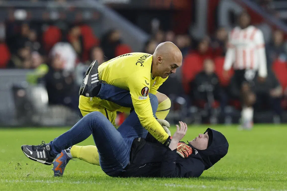 A pitch invader clashing with Sevilla goalkeeper Marko Dmitrovic during the closing stages of the Europa League match against PSV Eindhoven on Thursday.