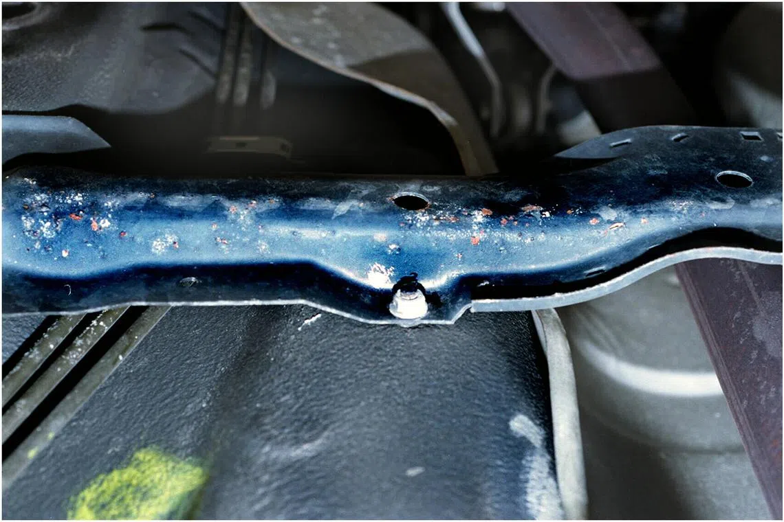 Rust spots on a car's undercarriage cross-bar.