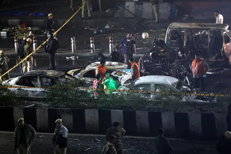 Indian police personnel inspect the scene of a blast near the red fort in New Delhi, India.