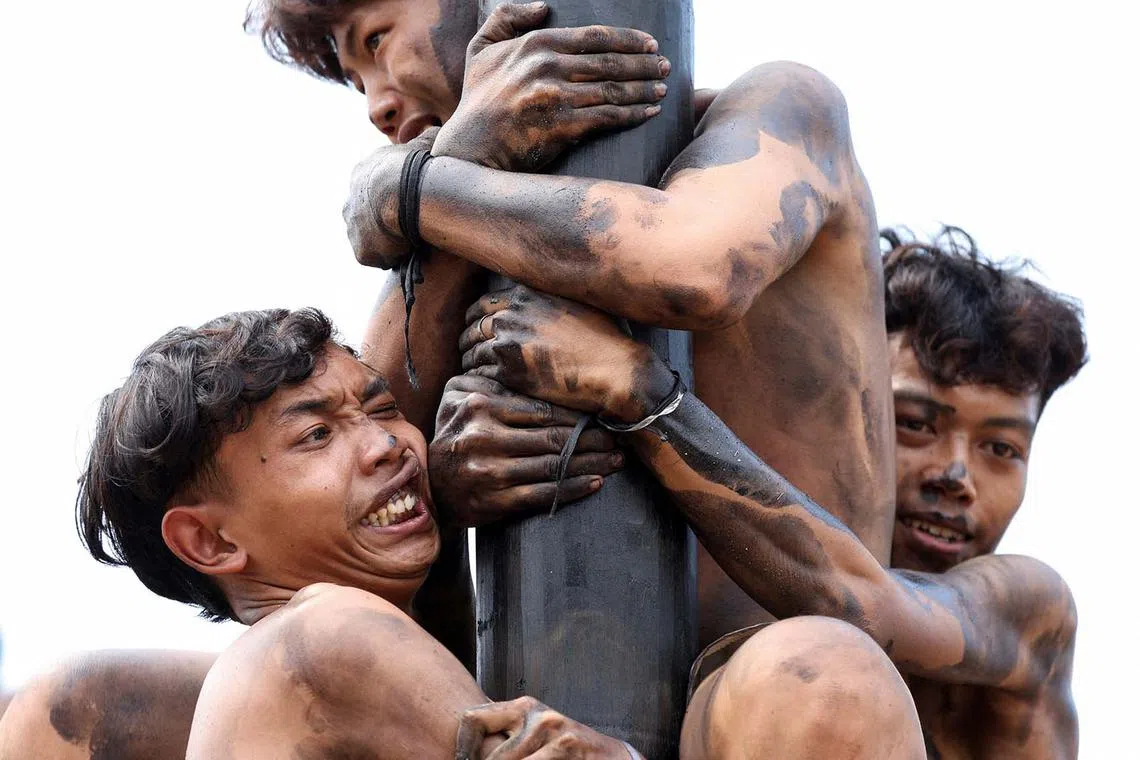Participants react as they try to reach the top of a greased pole to collect the prizes, during a "Panjat Pinang" competition, that is held to celebrate Indonesia's 79th Independence Day at Ancol in Jakarta, Indonesia, August 17, 2024. REUTERS/Ajeng Dinar Ulfiana TPX IMAGES OF THE DAY