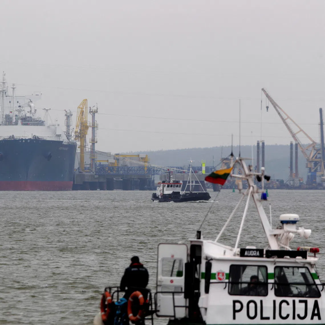 FILE PHOTO: A police boat is seen in the foreground of the floating storage regasification unit \"Independence\" on October 27, 2014, one of the key infrastructure objects in Lithuania now guarded by military due to fears of a Russian false-flag attack. REUTERS/Ints Kalnins/File Photo