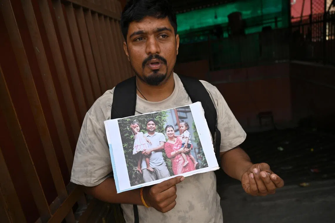 Sagar Poudel holding a family picture showing his cousin Somnath Poudel, an engineer who is missing in Trishuli 3B hydropower tunnel, his wife and twin daughters.