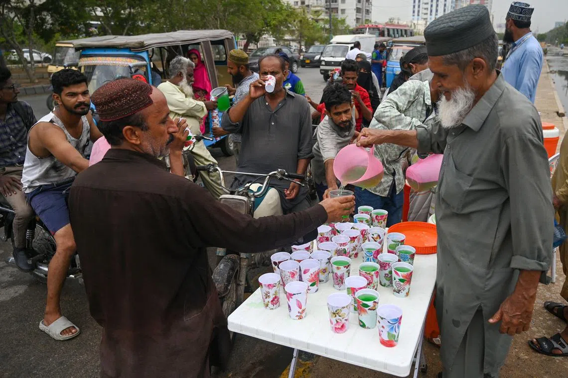 A man serves cold drinks to commuters along a street on a hot summer day in Karachi.