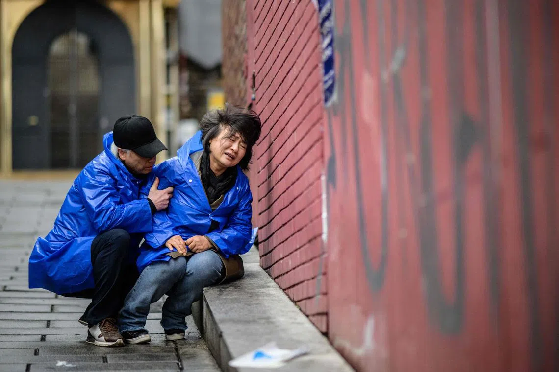 Madam Cho Mi-eun (R) crying as her husband Mr Lee Jong-chul kneels down while trying to comfort her on April 5, 2023, in the alleyway where their 24-year-old son Lee Ji-han was killed during a Halloween crowd crush in the popular Itaewon district of Seoul in October last year. 