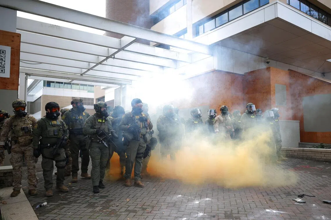 Law enforcement officers deploys a smoke grenade to disperse demonstrators gathering in front of law enforcement officers during a protest at the Immigration and Customs Enforcement headquarters in Portland, Oregon, on Oct 4, 2025. 