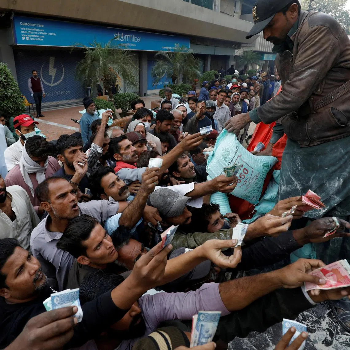 Men reach out to buy subsidised flour sacks from a truck in Karachi, Pakistan, on Jan 10, 2023.