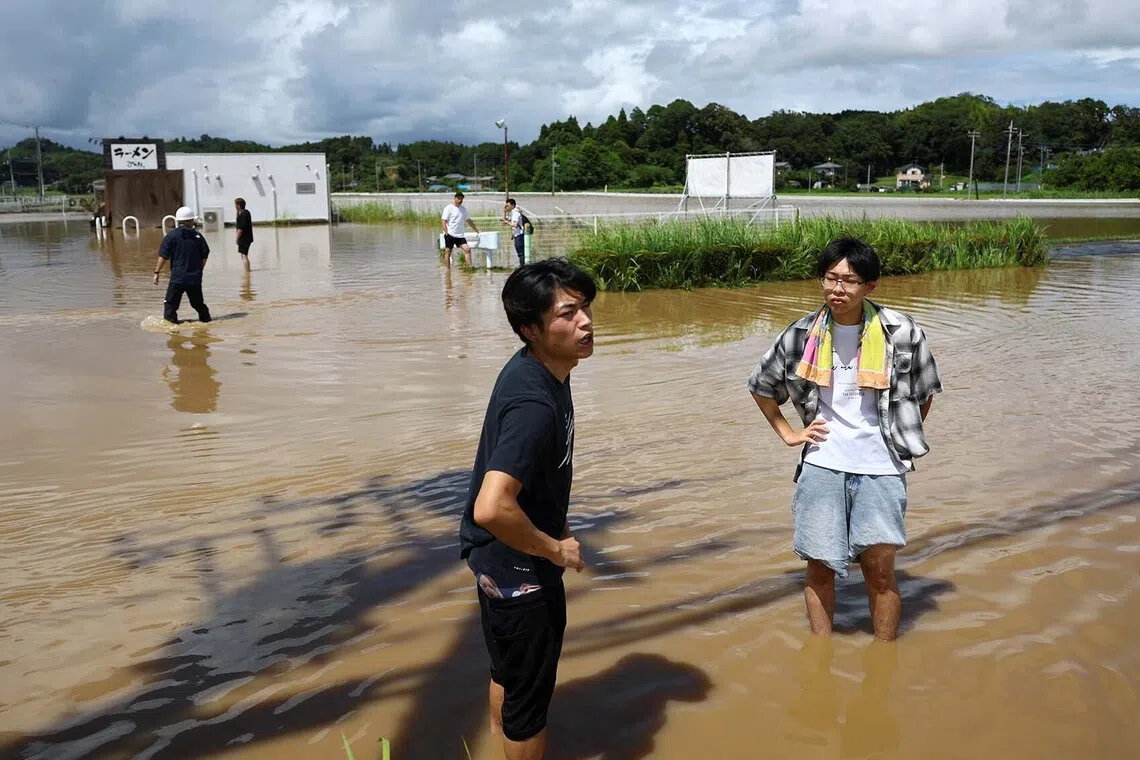 Local residents stand in a flooded area after heavy rain in Oamishirasato, Chiba Prefecture, Japan, August 14, 2026. REUTERS/Issei Kato