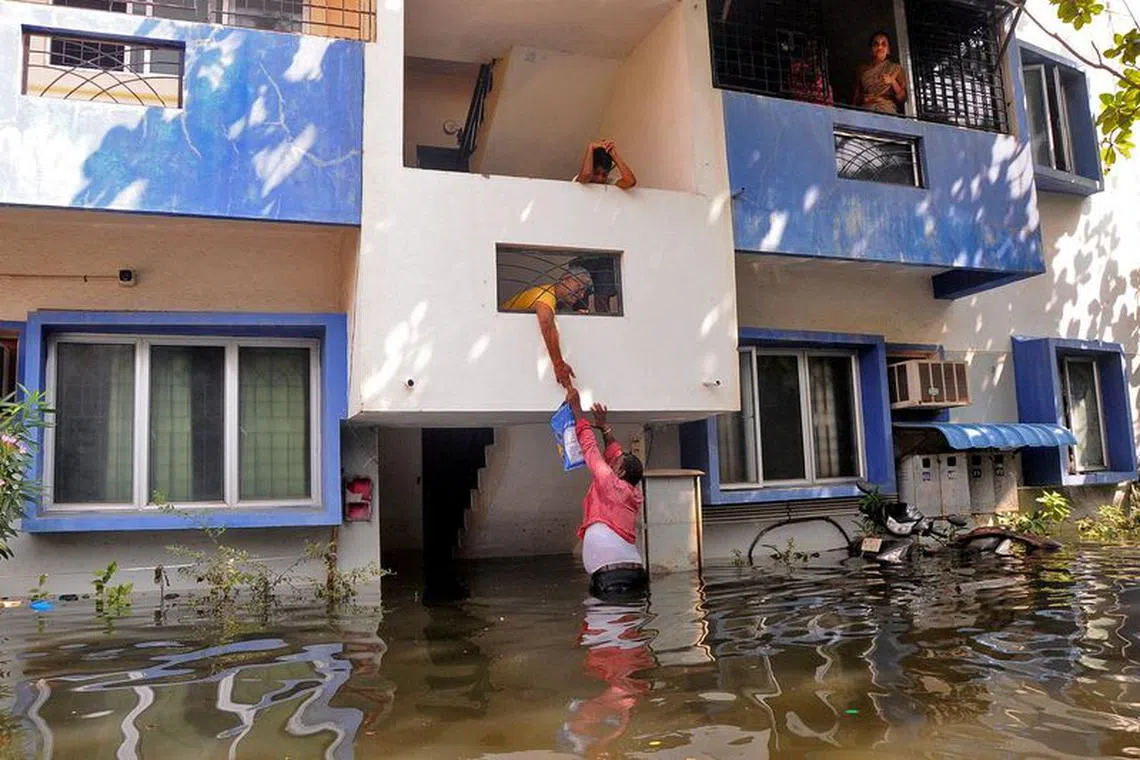 FILE PHOTO: A volunteer offers food to a resident after his house got partially submerged following heavy rains due to Cyclone Michaung, in Chennai, India, December 6, 2023. REUTERS/Stringer/File Photo