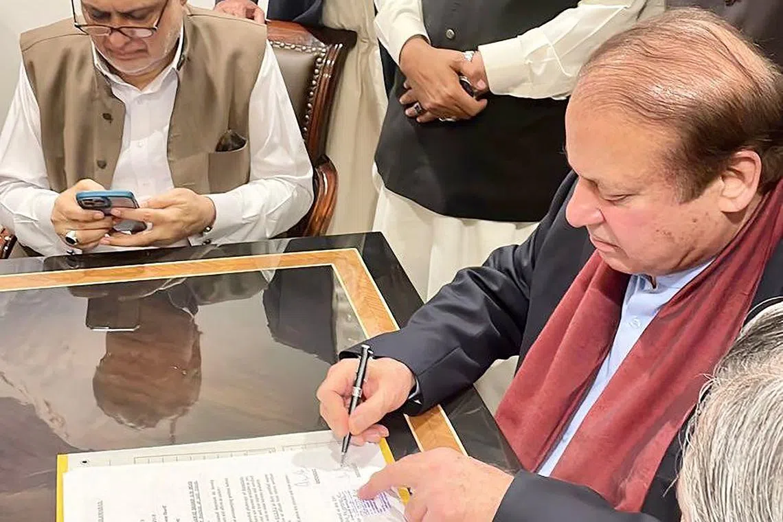 Former Pakistan PM Nawaz Sharif signing a legal document after his arrival at Islamabad airport on Oct 21.