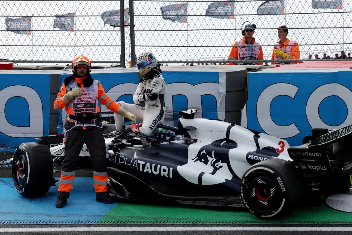 AlphaTauri's Daniel Ricciardo reacts after a crash during practice as a steward looks on.