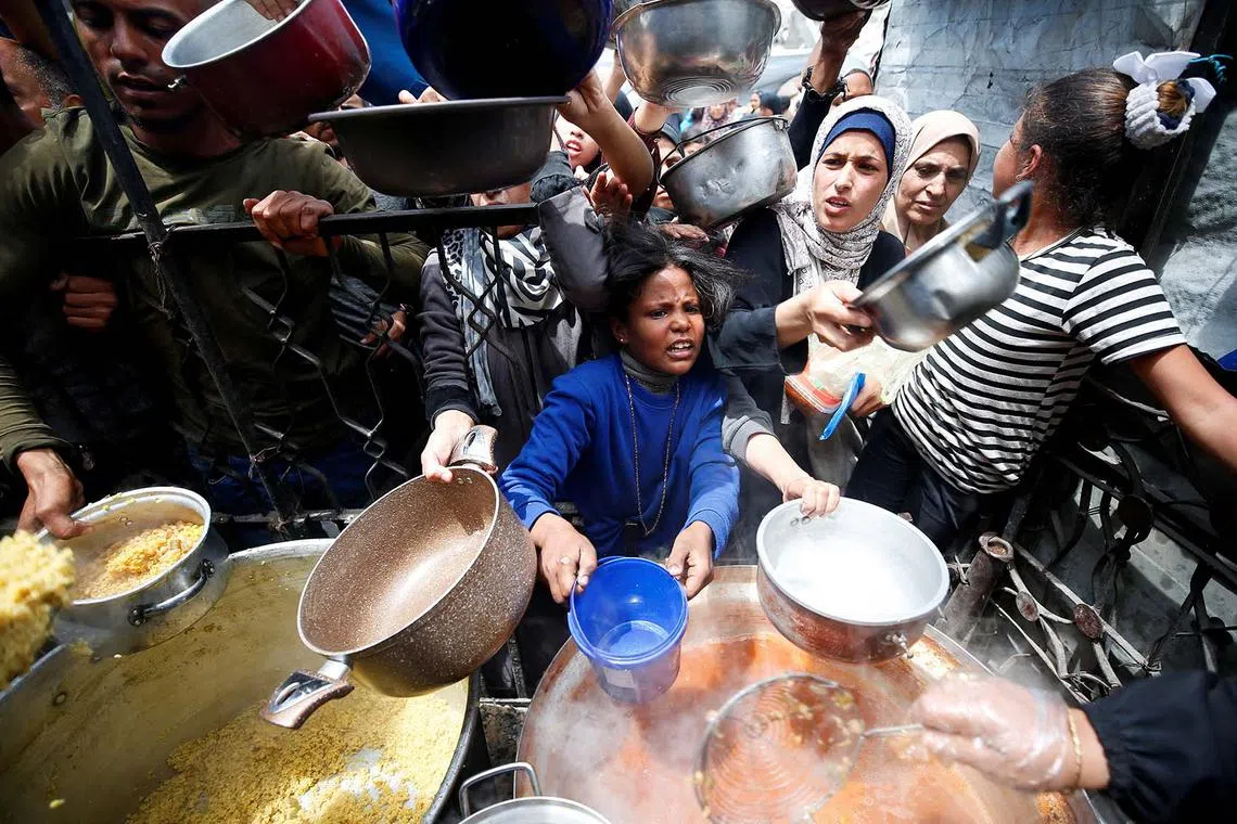 Palestinians waiting to receive food cooked by a charity kitchen, in Beit Lahiya, northern Gaza Strip, April 28, 2025. 