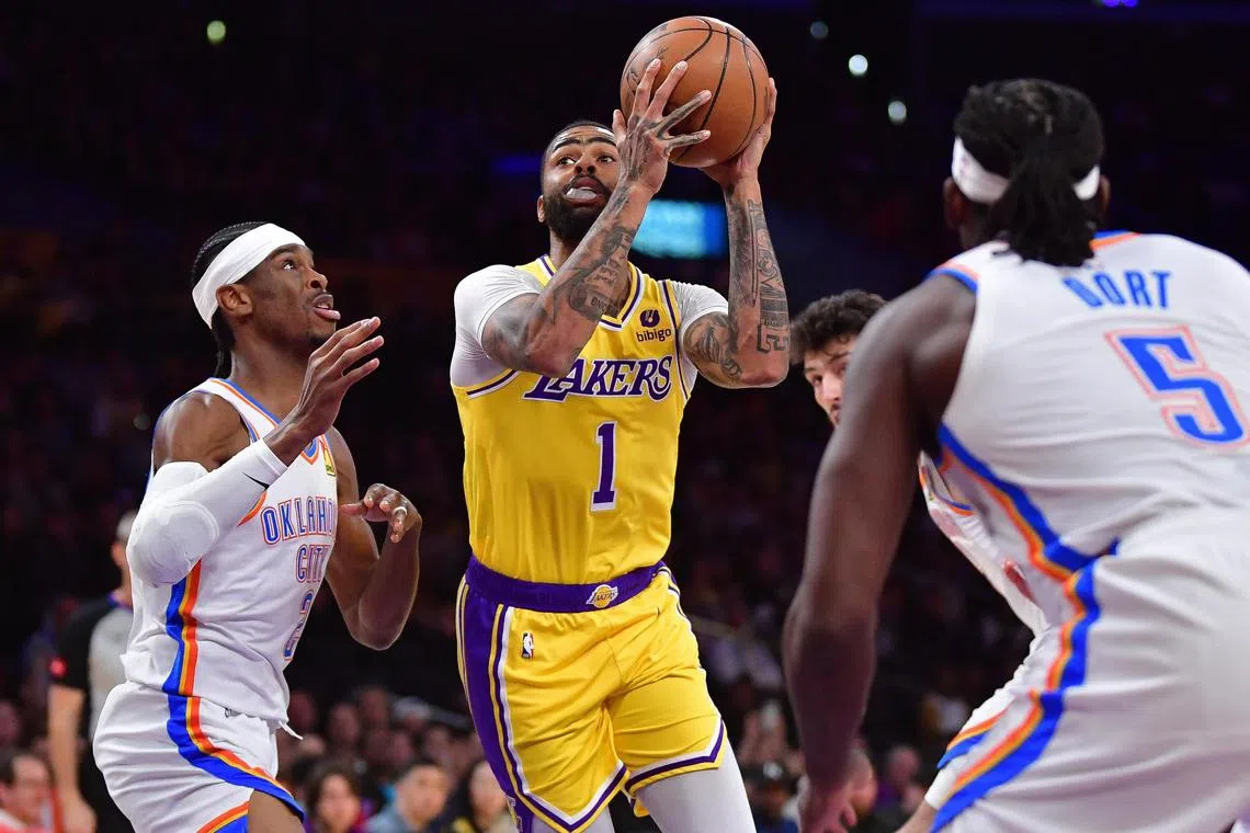 Los Angeles Lakers guard D'Angelo Russell drives to the basket against Oklahoma City Thunder's Shai Gilgeous-Alexander and Luguentz Dort during the first half at Crypto.com Arena.