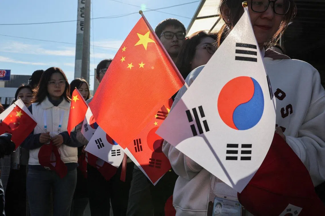 FILE PHOTO: Pro-China supporters hold China and South Korea flags near Gimhae International Airport ahead of a bilateral meeting between U.S. President Donald Trump and Chinese President Xi Jinping on trade tensions and bilateral relations, on the sidelines of the Asia-Pacific Economic Cooperation (APEC) Summit, in Busan, South Korea, October 30, 2025. REUTERS/Tyrone Siu/File Photo