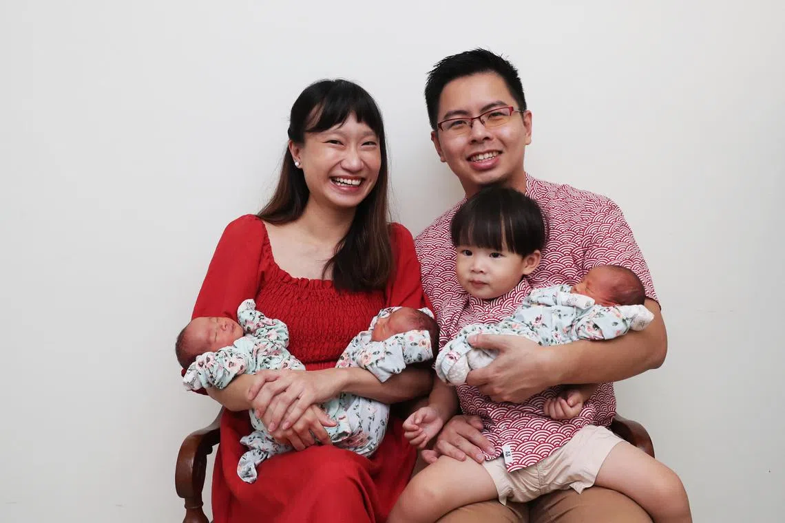 Dr Claire Low holding Gareth (left) and Kenneth, and Mr Edwin Chua with Seth and their two-year-old son, Keith.