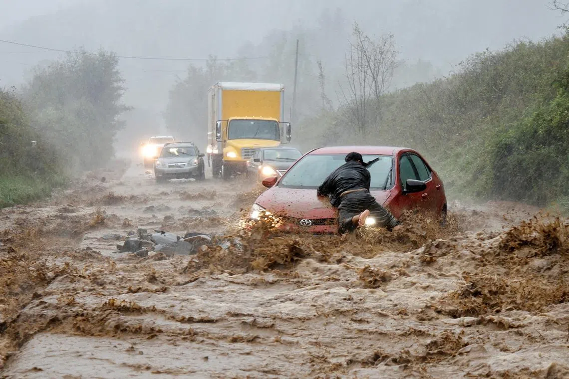 A local resident helps free a car that became stranded on a stretch of flooded road as Tropical Storm Helene struck, on the outskirts of Boone, North Carolina, on Sept 27.