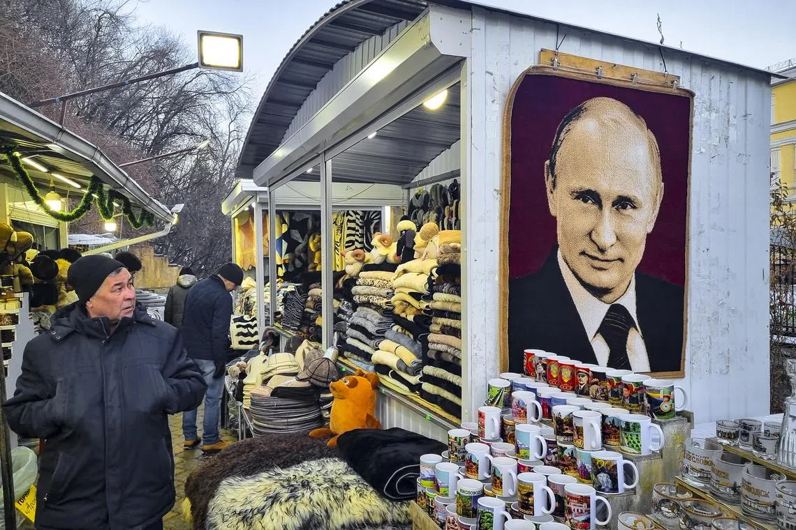 A man looks at a carpet with a portrait of Russian President Vladimir Putin at the street market in the centre of Kislovodsk, Russia, on Dec 26, 2022. 