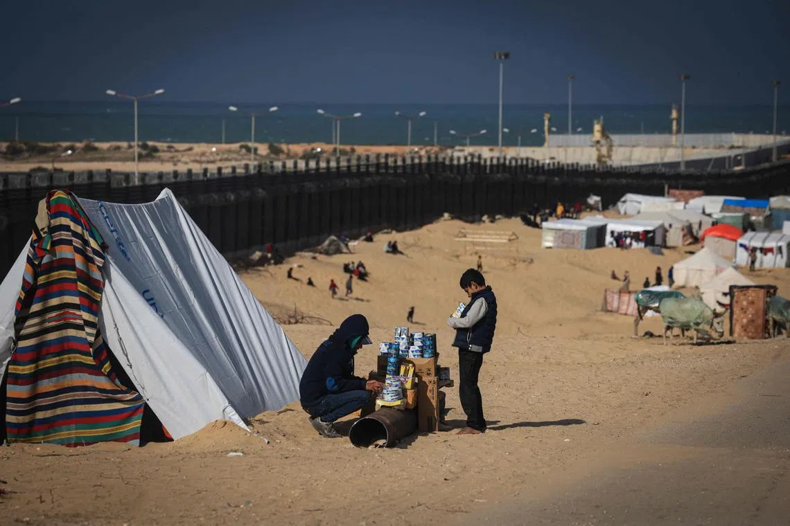 A displaced Palestinian displays some goods for sale at a makeshift camp in the Philadelphi, or Salaheddin, Corridor, a narrow buffer zone along the Gaza Strip's border with Egypt.