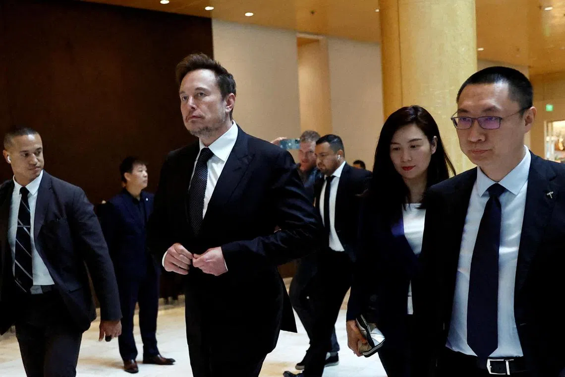 Tesla Chief Executive Officer Elon Musk walks next to Tesla's Senior Vice-President Tom Zhu and Vice-President Grace Tao as he leaves a hotel in Beijing, China.