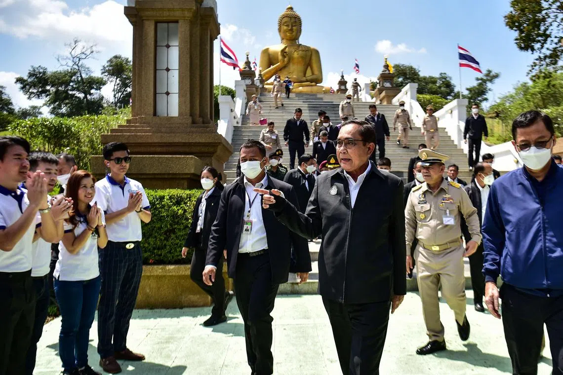 Thailand's Prime Minister Prayut Chan-O-Cha (3R) walks in front of the Golden Buddha statue as he visits Khao Kong temple in Narathiwat district, southern Thailand, on March 15, 2023. (Photo by Madaree TOHLALA / AFP)