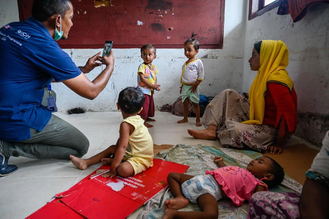An International Organization for Migration (IOM) officer photographs Rohingya refugees at a temporary shelter following their arrival by boat in Laweueng, Aceh province on December 27, 2022. 