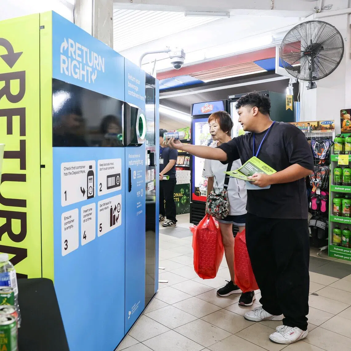 Mr Muhammad Sirajuddin Ibrahim (right), 29, a part-time events crew member, explaining the beverage container return scheme to members of the public outside the Sheng Siong outlet at Ang Mo Kio Avenue 4 on April 1, 2026. 