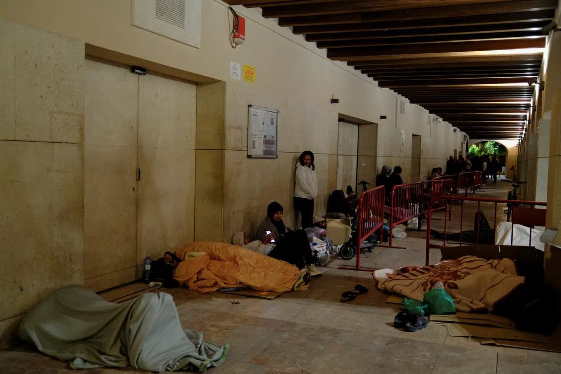 People rest as they wait in a queue in the early morning to obtain a vulnerability certificate to regularise their migration status, at the town hall of Almeria, Spain, April 21, 2026. REUTERS/Nacho Doce