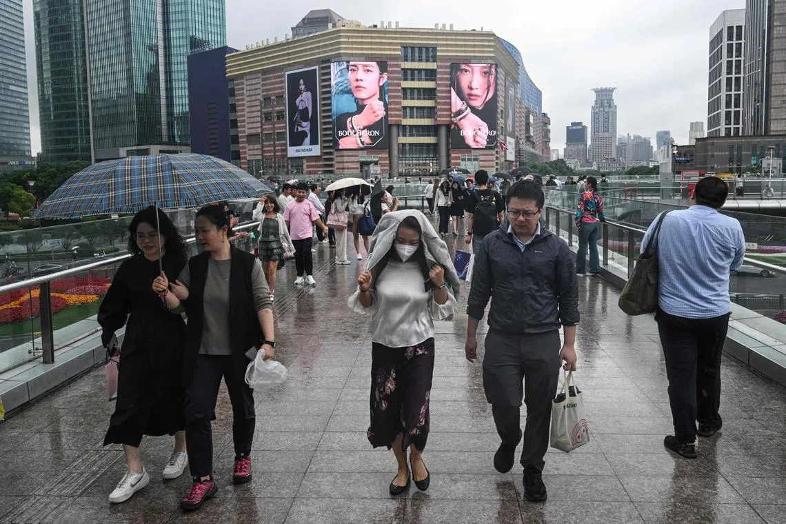 This photo taken on June 5, 2024 shows people walking on a bridge at the Lujiazui financial district in Shanghai. A year and a half after crippling Covid-19 restrictions ended, the property crisis is just one of the deadweights dragging on China's recovery momentum, sending ripples of unease through the country's leaders and citizens. (Photo by HECTOR RETAMAL / AFP) / To go with 'CHINA-ECONOMY-POLITICS, FOCUS' by Peter Catterall, and Rebecca Bailey in Shanghai