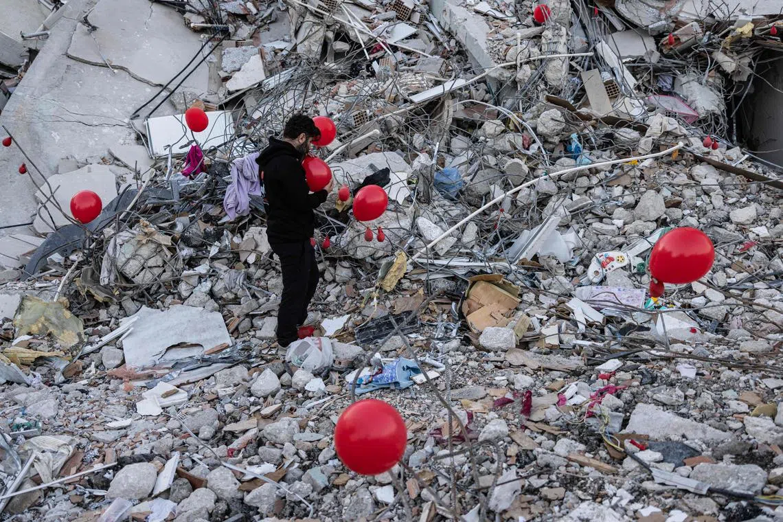 Ogun Sever Okur, a 38-year-old Turkish man inflates balloons on the debris of a collapsed building in Antakya, southern Turkey on Feb 21, 2023, following the 6.4-magnitude earthquake which struck on February 20, two weeks after a 7.8-magnitude earthquake hit near Gaziantep and has killed more than 44,000 people. On the side of a busy road in Antakya, dozens of red balloons flutter around, hanging from the ruins. They are "the last toys" of children who died during the earthquake that devastated this southern Turkish city, explains Ogun Sever Okur, the author of this posthumous gift. 