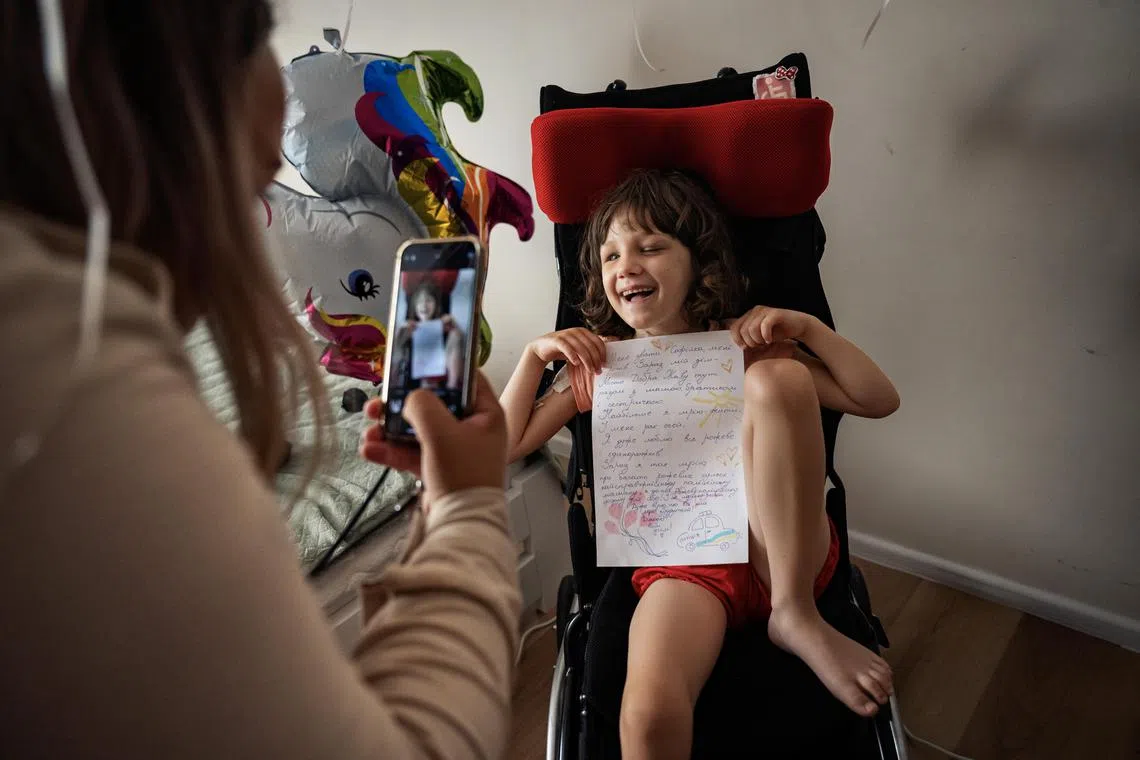 Sonya Liakh, aged 5 and in palliative cancer care, holds up a letter describing her dreams a few days after doctors transitioned her treatment to a fentanyl patch in addition to morphine, at the City of Goodness shelter in Chernivtsi, Ukraine, June 27, 2024. The daunting health challenges facing sick and disabled children in Ukraine are a cruel reminder that the warÕs tentacles stretch far beyond the front line. (Lynsey Addario/The New York Times) Ñ NO SALES


