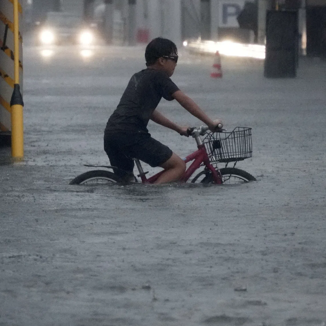 A boy cycles through a flooded street as Typhoon Dujuan brings heavy rain, in Ichikawa, Chiba Prefecture, Japan, September 21, 2026 in this photo taken by Kyodo. Kyodo via REUTERS